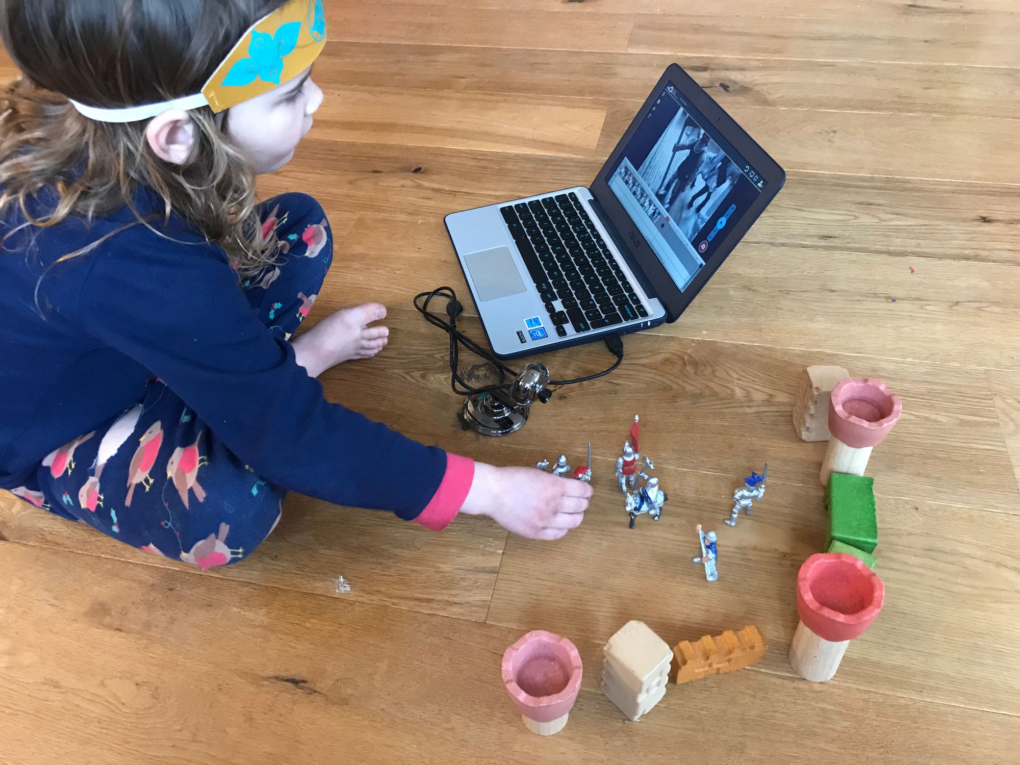 Young child animating models on the floor with a Chromebook and webcam