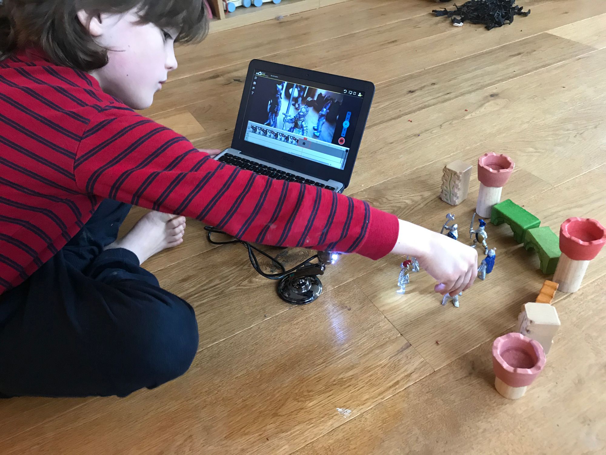 Young child animating their models with Cloud Stop Motion on the floor